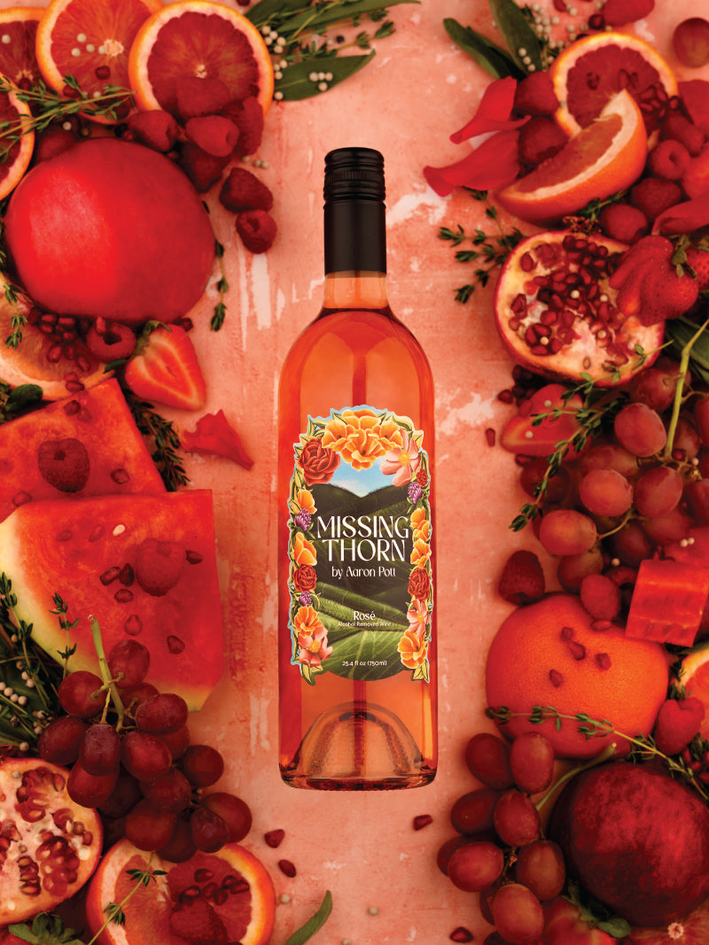 Bottle of Missing Thorn wine surrounded by fruits on a pink background