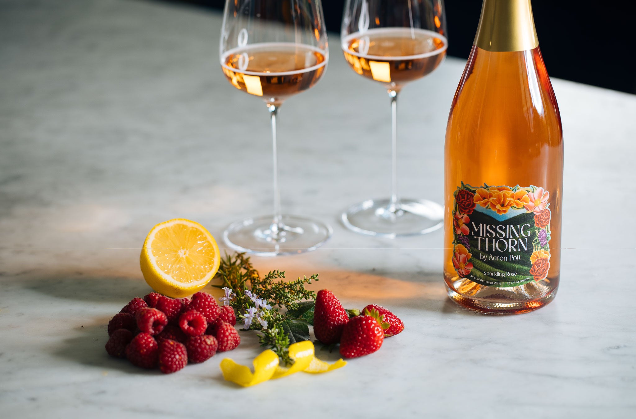 Bottle of 'Missing Horn' rosé wine with two glasses and fruits on a marble surface