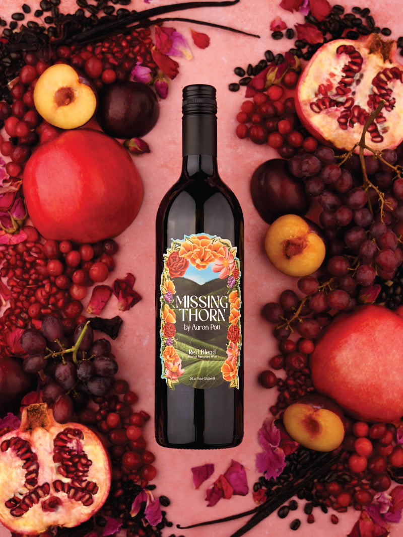 Bottle of 'Missing Thorn' wine surrounded by fruits on a pink background