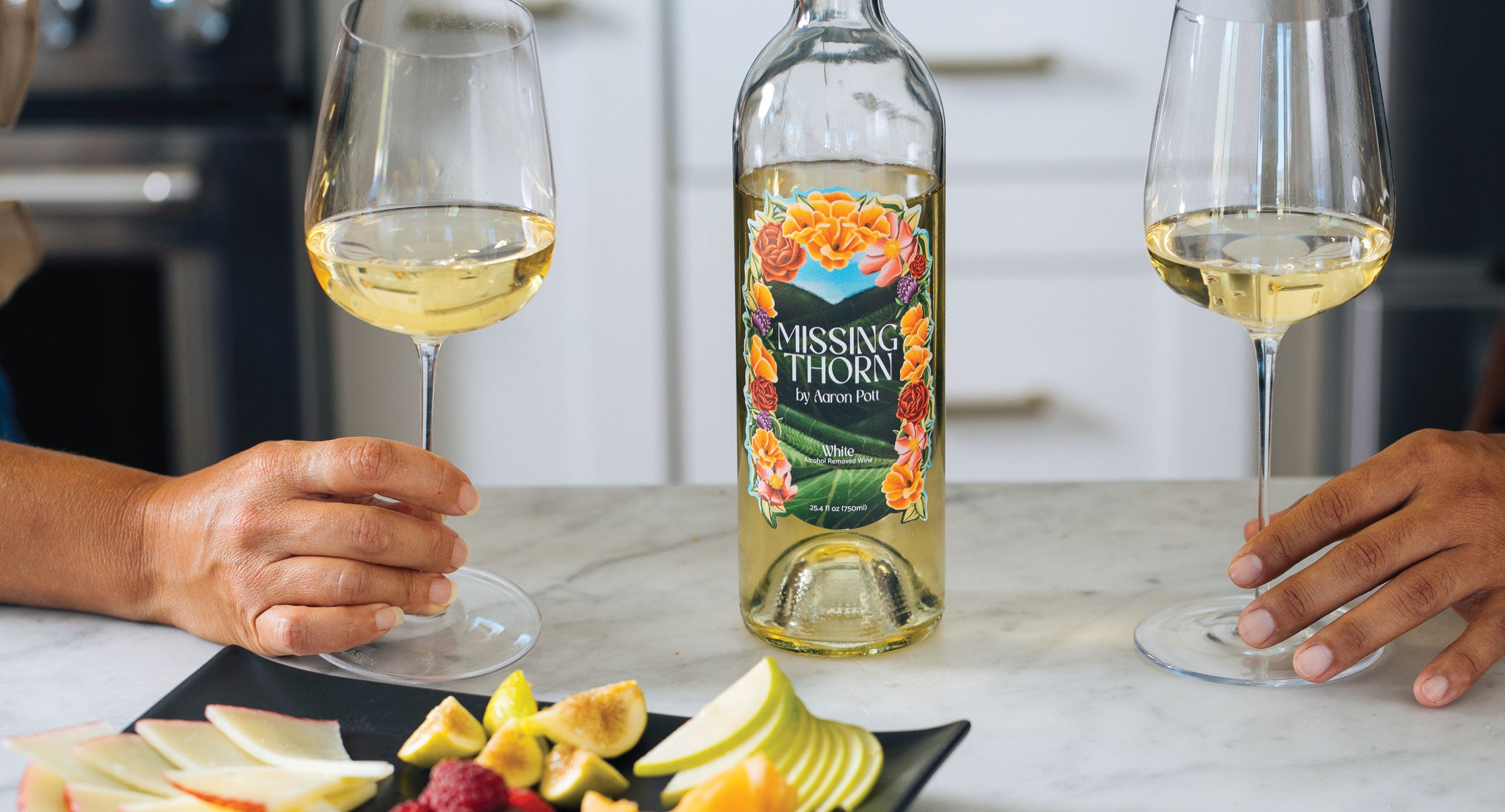 Bottle of 'Missing Thorn' wine with two glasses of white wine on a kitchen counter.
