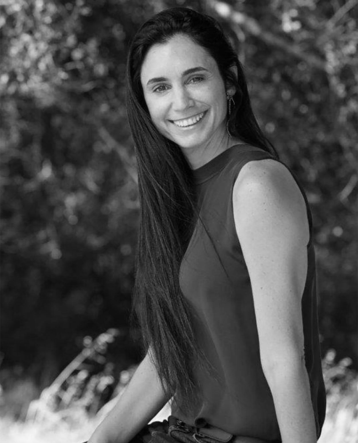 Black and white portrait of a woman with long hair sitting outdoors.